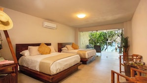 A hotel room with two beds, a wooden chair, a table, and a view of greenery outside. - Corrales Bay Resort (Los Corrales)