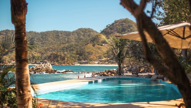 A clear blue pool with a view of the sea and a mountainous backdrop. - Corrales Bay Resort (Los Corrales)