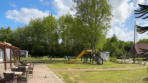 Eine Terrassenanlage mit Sitzgelegenheiten und einem Spielplatz mit Rutsche.