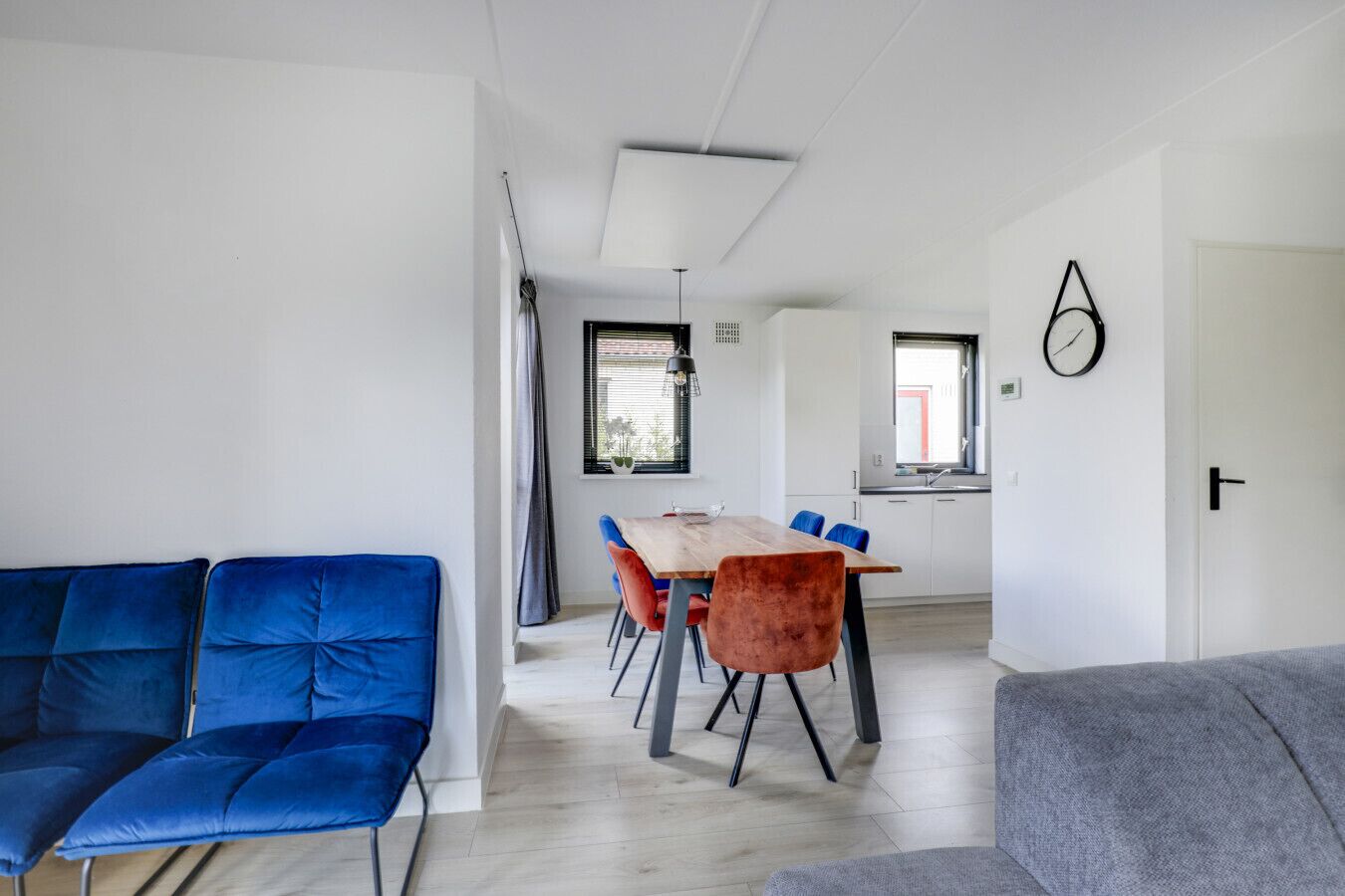 Un soggiorno moderno con zona pranzo, divani blu e grigi e un tavolo in legno.