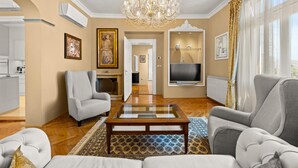 A living room with a chandelier, two armchairs, a coffee table, and a TV mounted on the wall. - Luxurious home in Opatija with private swimming pool, can be inside or outside (Opatija)