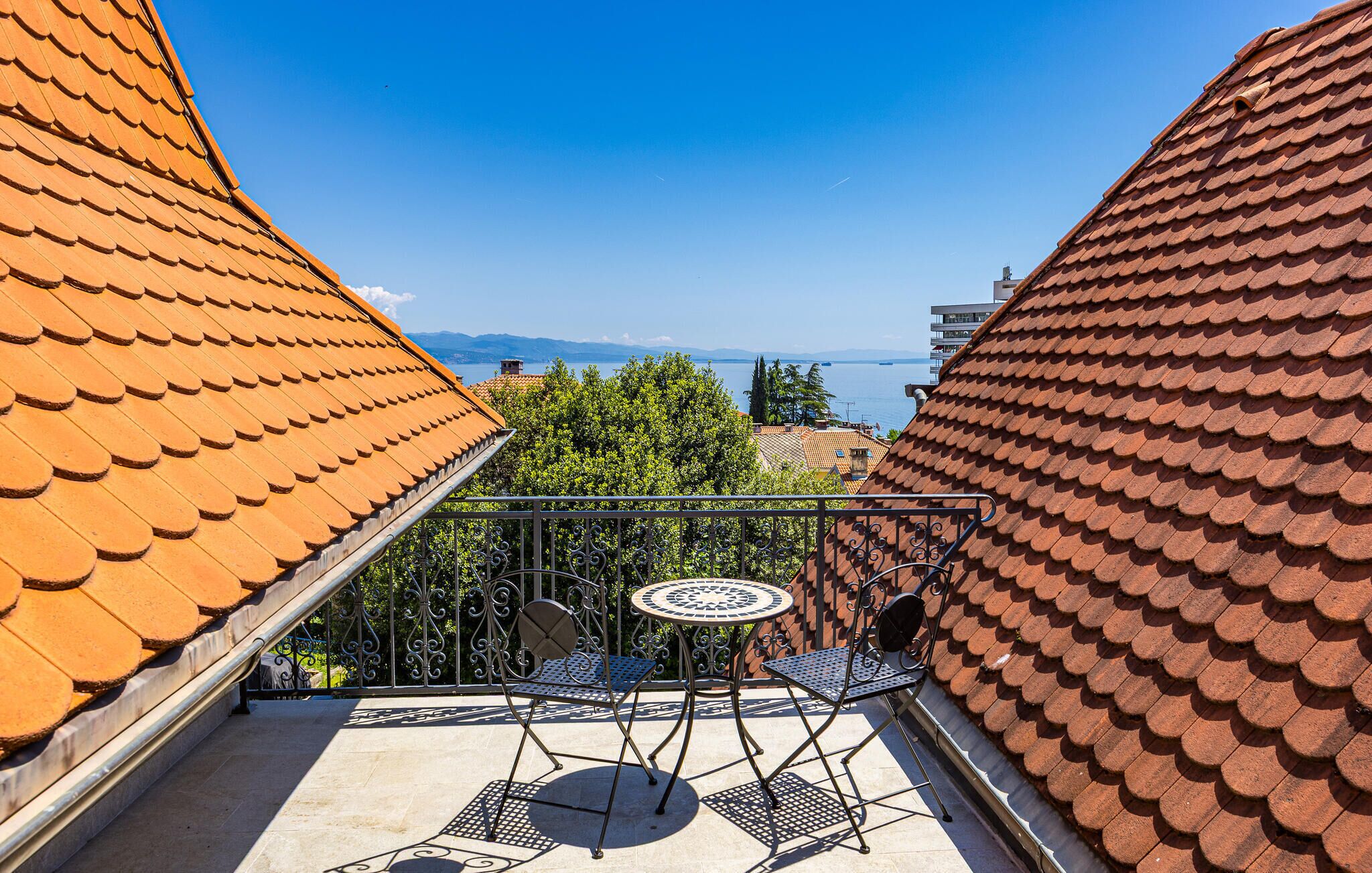 Varanda com vista para o mar, com grade de metal e duas cadeiras.