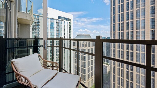 Ein Balkon mit Korbstühlen und Blick auf hohe Gebäude.