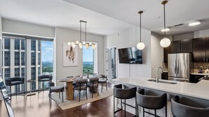Eine moderne Küche mit einer großen Kochinsel, Edelstahlgeräten und Blick auf die Stadt.