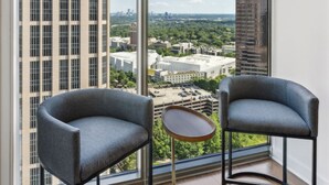 Ein modernes Zimmer mit zwei Sesseln und einem kleinen Tisch, große Fenster mit Blick auf die Stadt.