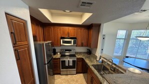 A kitchen with wooden cabinets, stainless steel appliances, and a granite countertop. - Luxurious Condo 2BD/2BA w/ Pool, Gym, and Sauna (Scottsdale)