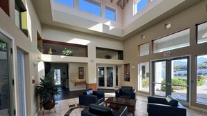 A spacious lobby with a high ceiling, multiple seating areas, and large windows offering views of the outdoors. - Luxurious Condo 2BD/2BA w/ Pool, Gym, and Sauna (Scottsdale)