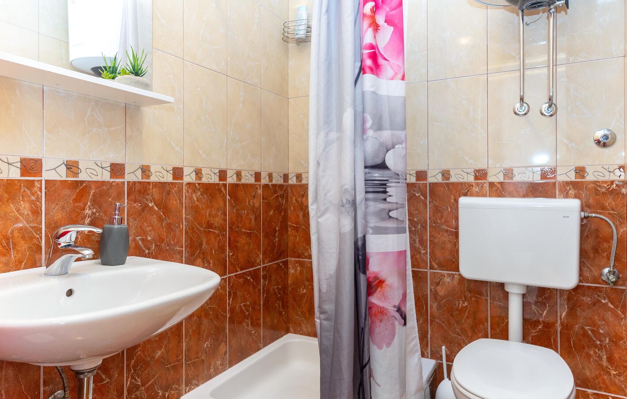 A bathroom with a white sink, a toilet, and a shower area.