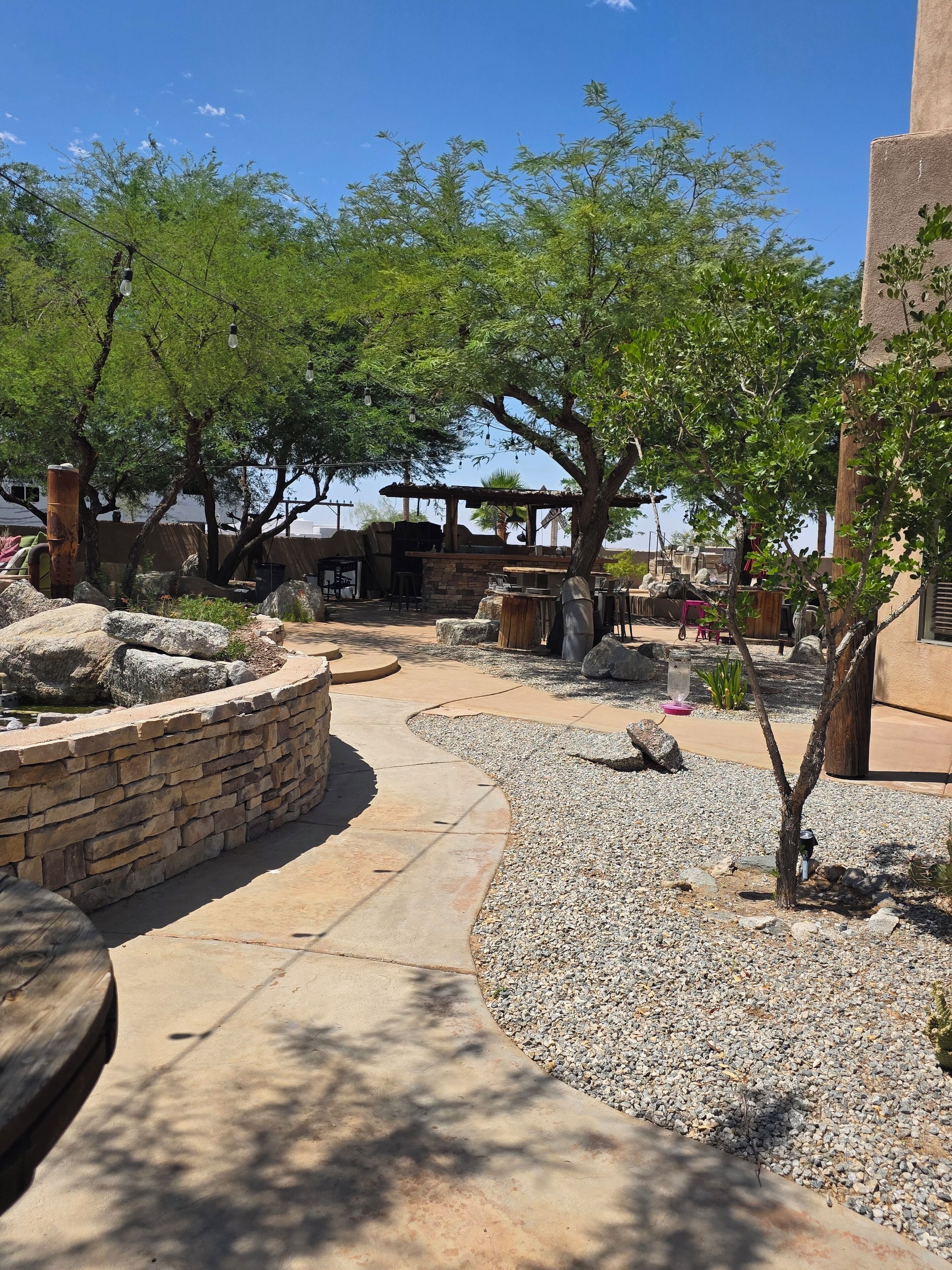 An outdoor patio area with a stone wall, seating, and a grill.