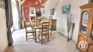 A dining area with a wooden table and chairs, a fireplace, and a view of the kitchen.