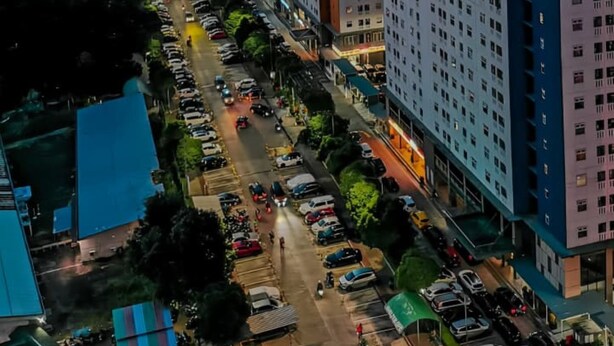 A high-rise building with multiple floors, surrounded by a parking lot and a cityscape in the background. - Cozy Superior Studio at Apartment Green Pramuka City by SHI (Jakarta)