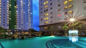 A hotel with a swimming pool, surrounded by high-rise buildings. - Cozy Superior Studio at Apartment Green Pramuka City by SHI (Jakarta)