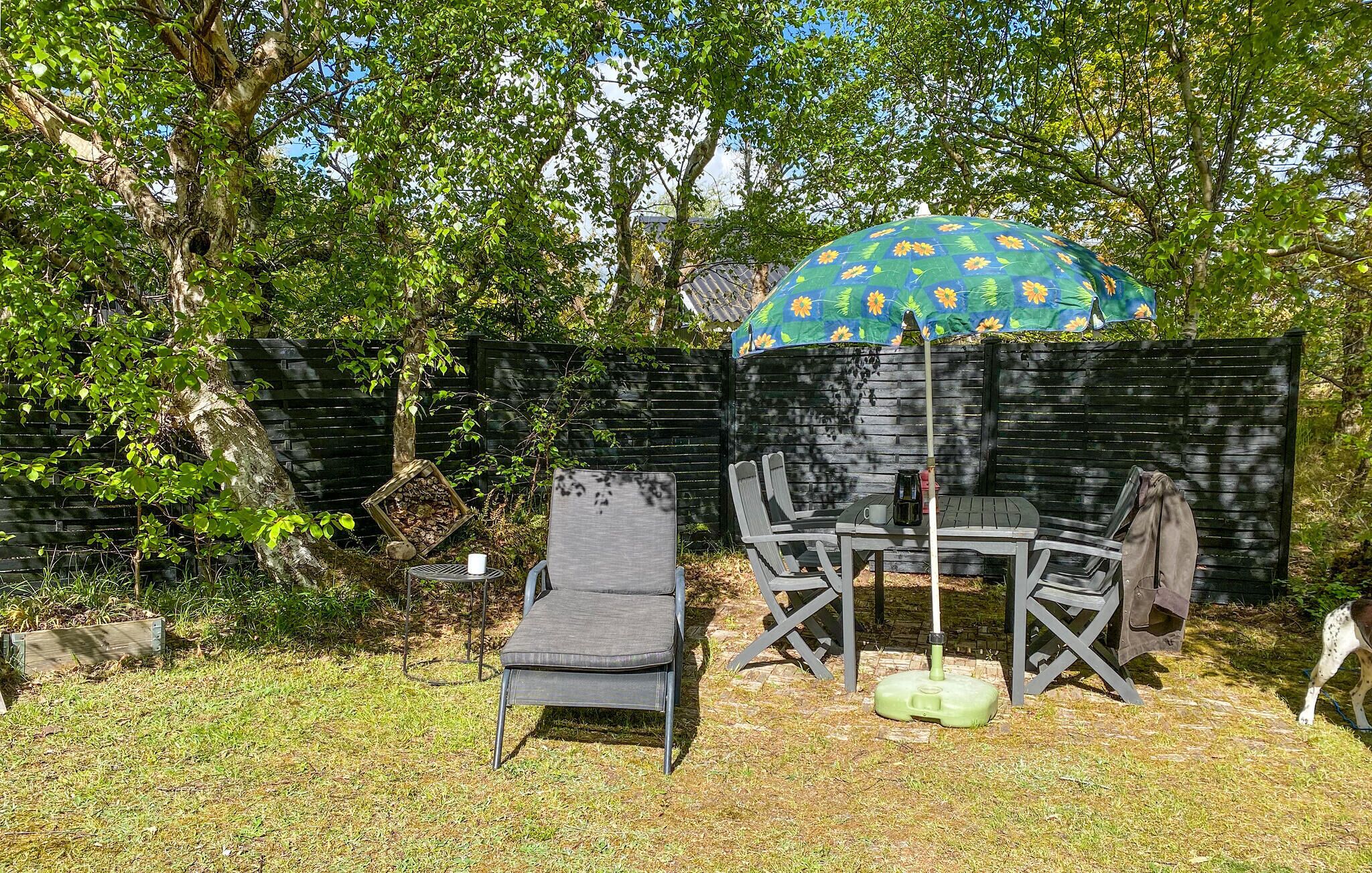 An outdoor seating area with a table and chairs, a decorative umbrella, and a fire pit.