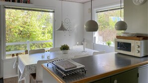A kitchen with a central island, a microwave, and a dining area with a table and chairs. - Amazing home in Glesborg with WiFi (Glesborg)