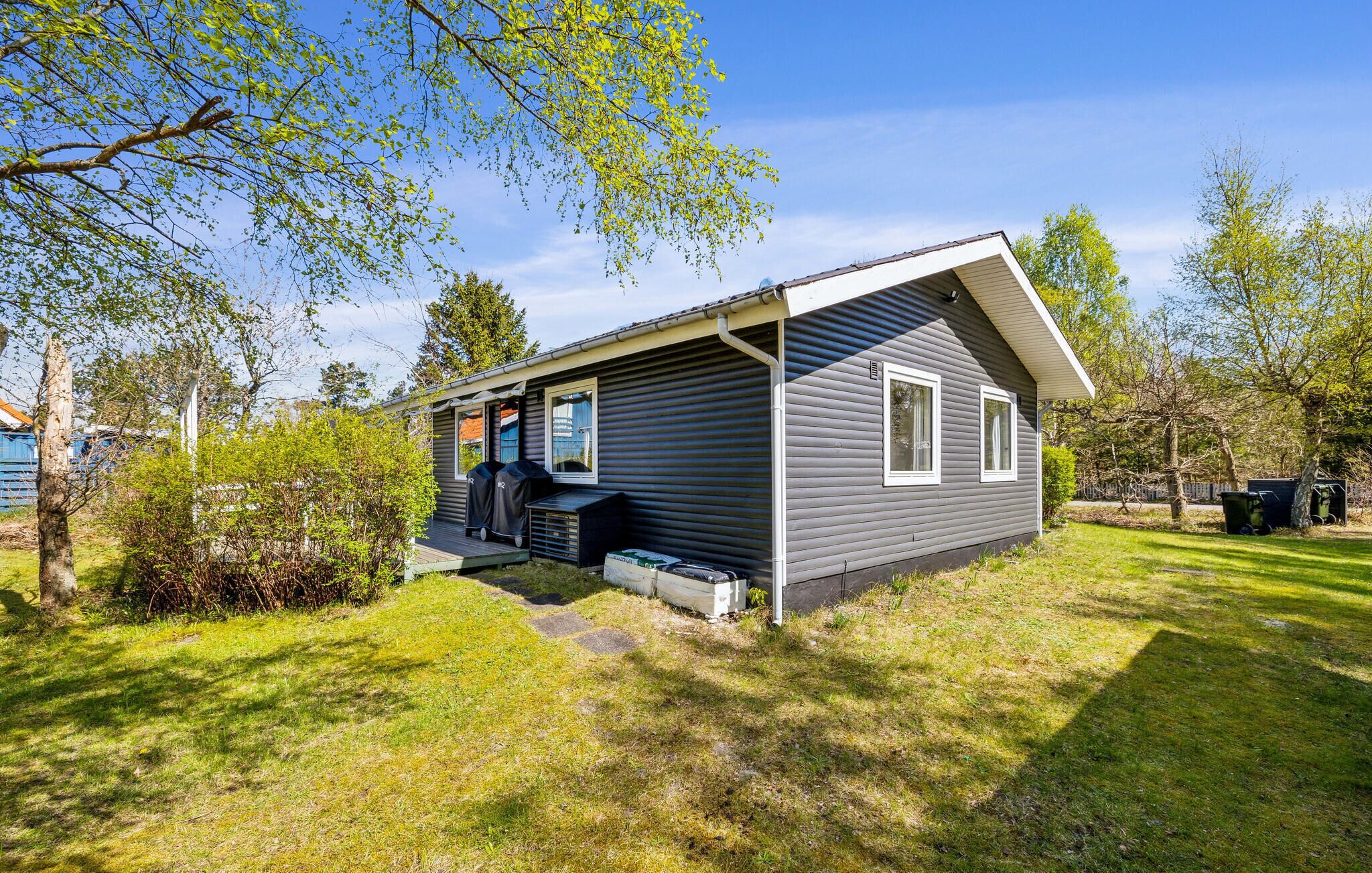 Une cabane de plain-pied dotée d’un porche couvert, d’une petite terrasse et d’un espace barbecue.