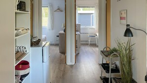A narrow hallway with a white refrigerator, a small table with a chair, and a hanging coat rack. - Amazing home in Glesborg with WiFi (Glesborg)