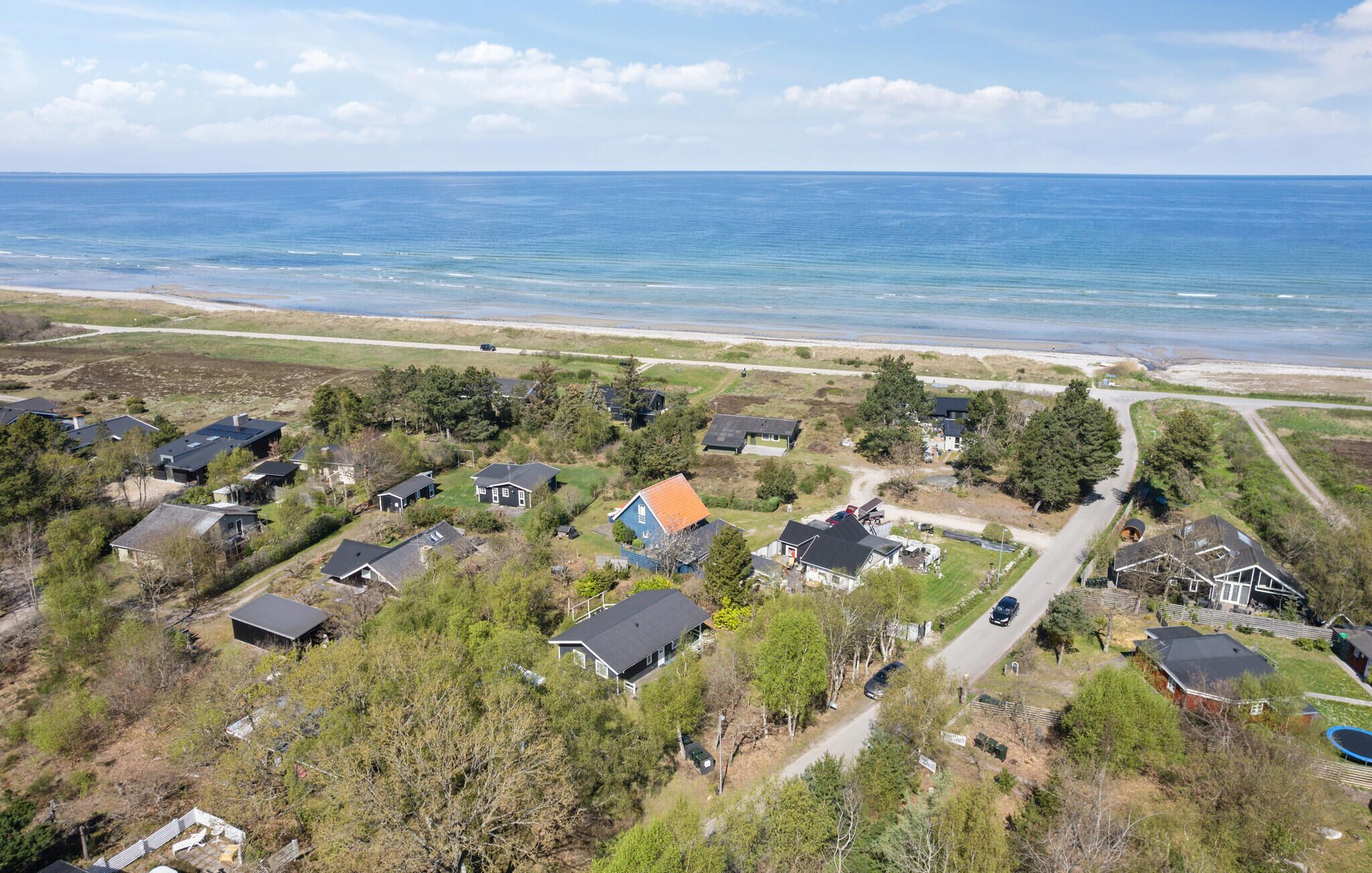 Ein Luftbild einer Küstenwohngegend mit Häusern, einer Straße und einem Strand.