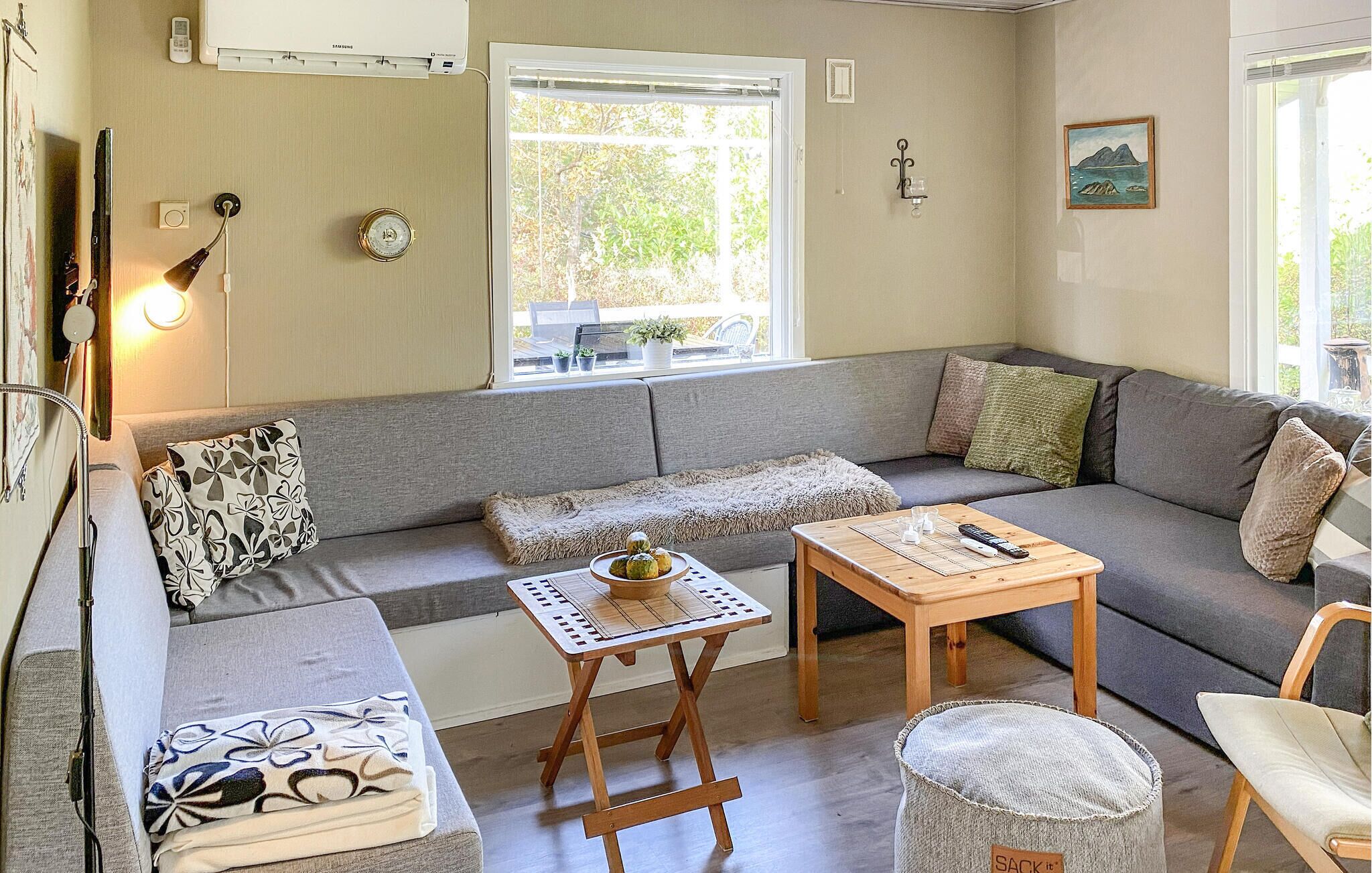 A cozy living room with a grey sofa, a small wooden table, and a cushioned chair.