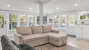 A spacious living room with a large sectional sofa, a grey couch, and a patterned rug.