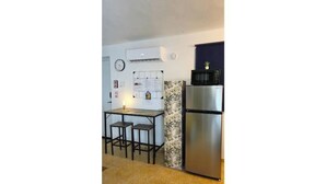 A compact kitchen with a refrigerator, a microwave, and a small dining area with stools. - Studio Apt in Añasco beach 15min drive to Rincon (Añasco)