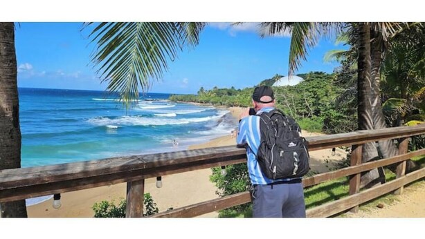 A person standing on a wooden deck overlooking a beach with palm trees and ocean waves. - Studio Apt in Añasco beach 15min drive to Rincon (Añasco)