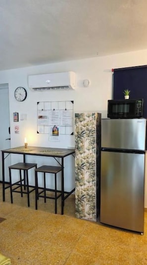 A compact kitchen with a refrigerator, a microwave, and a small dining area with stools. - Studio Apt in Añasco beach 15min drive to Rincon (Añasco)