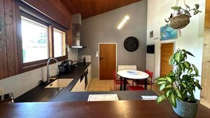 A kitchen with wooden cabinets, a sink, and a dining area with a round table and chairs.