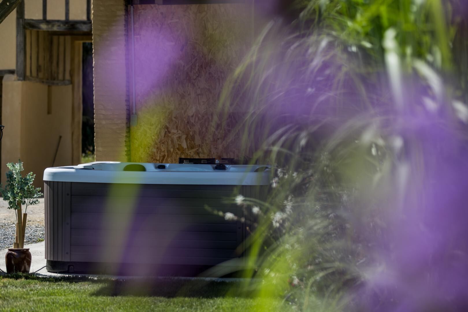 A hot tub in a garden with a house in the background.