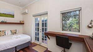 A bedroom with a bed, a desk, a chair, a window with a view, and a door leading to an outdoor area. - UrbanStyle Claremont Apartment (Mount Claremont)