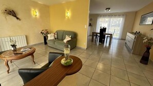A living room with a sofa, a coffee table, and a dining area with a table and chairs. - Gite Montanet - MEES (MEES)