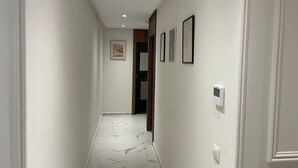 A hallway with white walls, a marble floor, and framed pictures on the wall. - Charming 2-room Apartment in Heart of Rabat (Rabat)