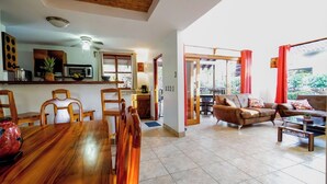 A spacious living area with a wooden dining table, a brown leather sofa, and a glass coffee table. - Casa Tropical - Fully equipped house with private pool and BBQ (Villareal Tamarindo)
