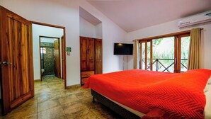 A hotel room with a large bed, wooden wardrobe, a television, and a balcony with a view. - Casa Tropical - Fully equipped house with private pool and BBQ (Villareal Tamarindo)