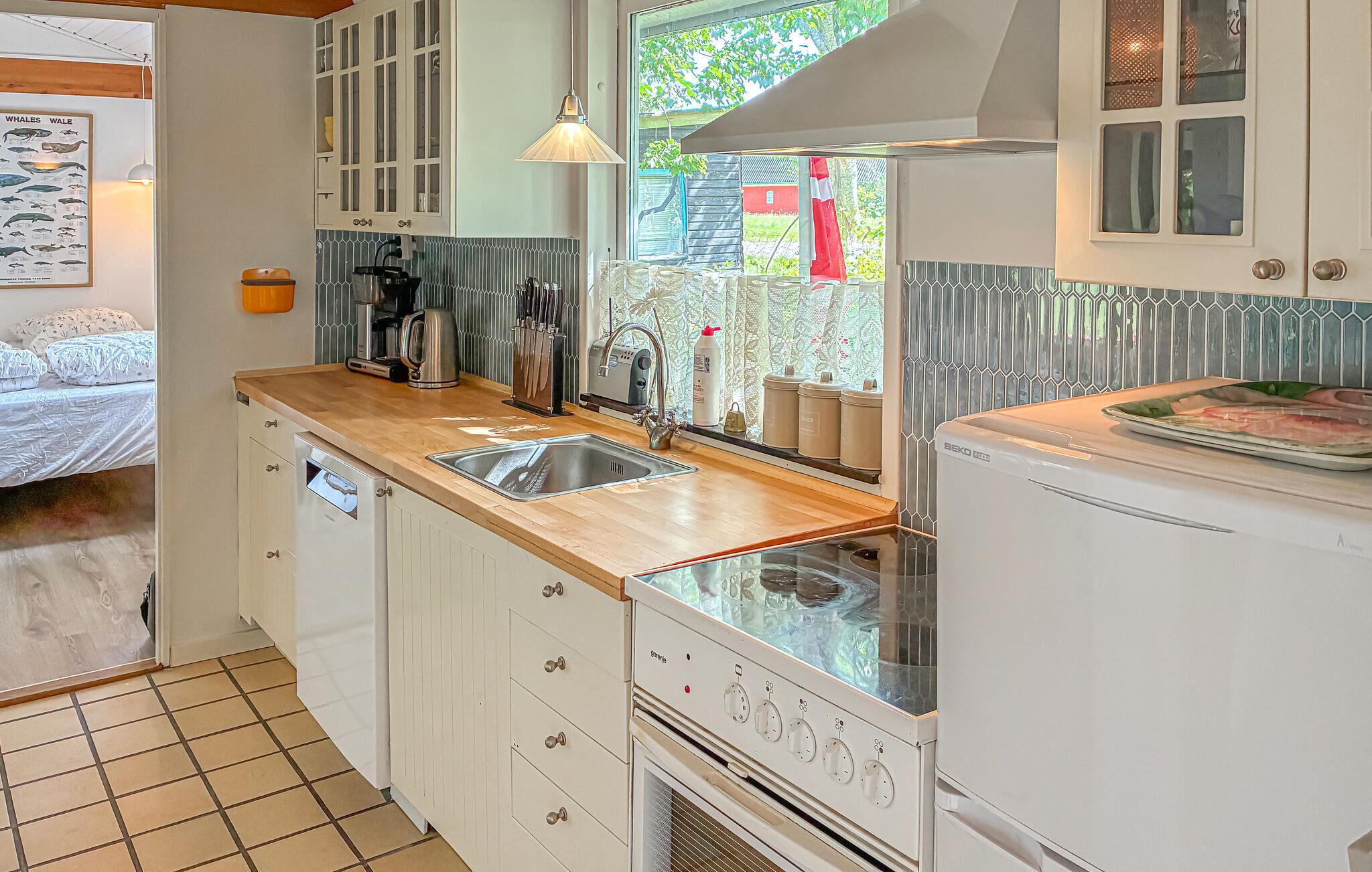 Een kleine keuken met een houten aanrecht, een spoelbak, een kookplaat en een koelkast.
