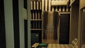 Ein kleines Zimmer mit einem Bett, einem kleinen Tisch, einem Schrank und einer Heizung.