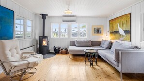 Un salon chaleureux avec un poêle à bois, un canapé, un fauteuil et une table.