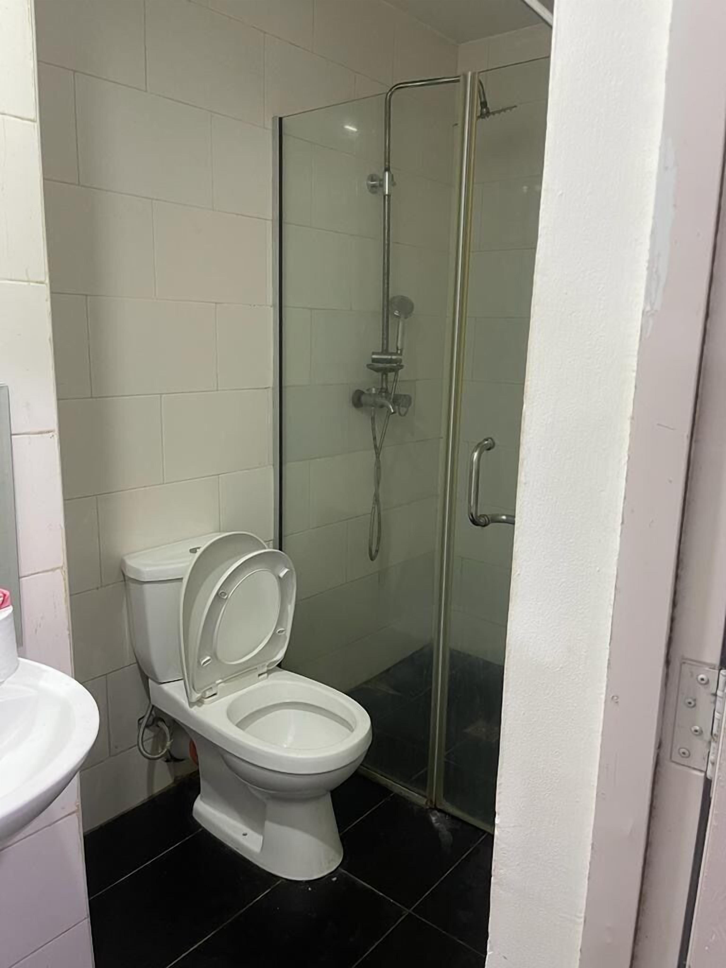A bathroom with a toilet, a glass shower enclosure, and white tiled walls.