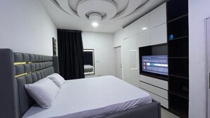 Een moderne slaapkamer met een bed, een ingebouwde televisie en een kledingkast.