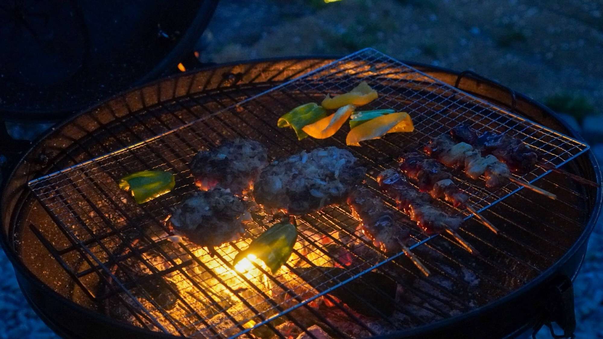 Una parrilla con carne y verduras asándose.