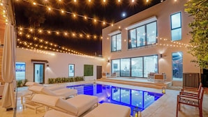 An indoor pool area with lounge chairs, string lights, and a view of the city. - Luxury Heated Pool + BBQ + 15 Min To Beach (Miami)