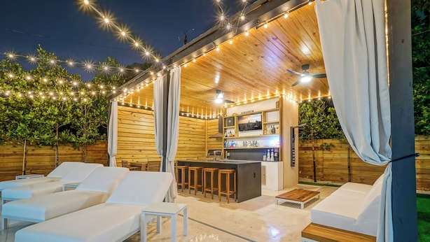 An outdoor lounge area with white cushioned chairs, a bar with stools, and string lights. - Luxury Heated Pool + BBQ + 15 Min To Beach (Miami)