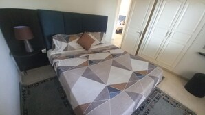 Ein Schlafzimmer mit einem Bett, einem Nachttisch, einer Lampe, einem Kleiderschrank und einer Tür.