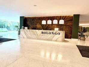 A reception desk with the name "BOLONGO" in a modern lobby with marble flooring and a large wall mural. - Luxury 2BR Bolongo Ocean View Private Beach (Punta de Mita)