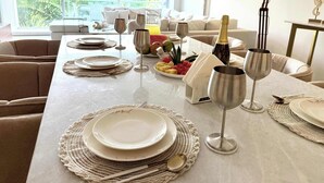 A dining area with a table set for a meal, a bottle of champagne, and a view of greenery outside. - Bolongo: Your Exclusive Oceanfront Escape (Sayulita)