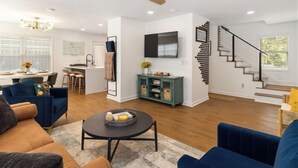 Un salon moderne avec un canapé, une table basse et un coin repas, la cuisine étant visible à l’arrière-plan.