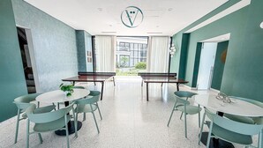 Une salle de conférence moderne, dotée d’une grande table et de chaises, offrant une vue sur l’extérieur et dont le plafond est orné d’un logo circulaire.