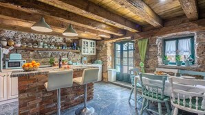 A rustic kitchen with a brick island, bar stools, and a stone wall.