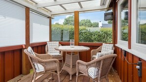 A covered patio with wicker furniture and a table, large windows, and a view of greenery. - Pet friendly home in Haderslev with WiFi (Haderslev)