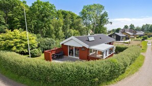 A modern house with a patio, surrounded by a well-maintained hedge, and a gravel driveway. - Pet friendly home in Haderslev with WiFi (Haderslev)