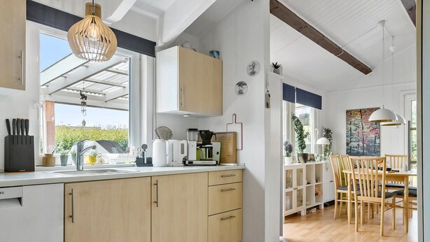 A modern kitchen with wooden cabinets, a built-in oven, and a dining area with wooden chairs and a table. - Pet friendly home in Haderslev with WiFi (Haderslev)